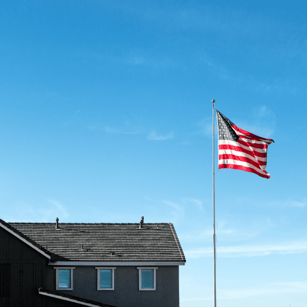 American flag flying beside house under blue sky