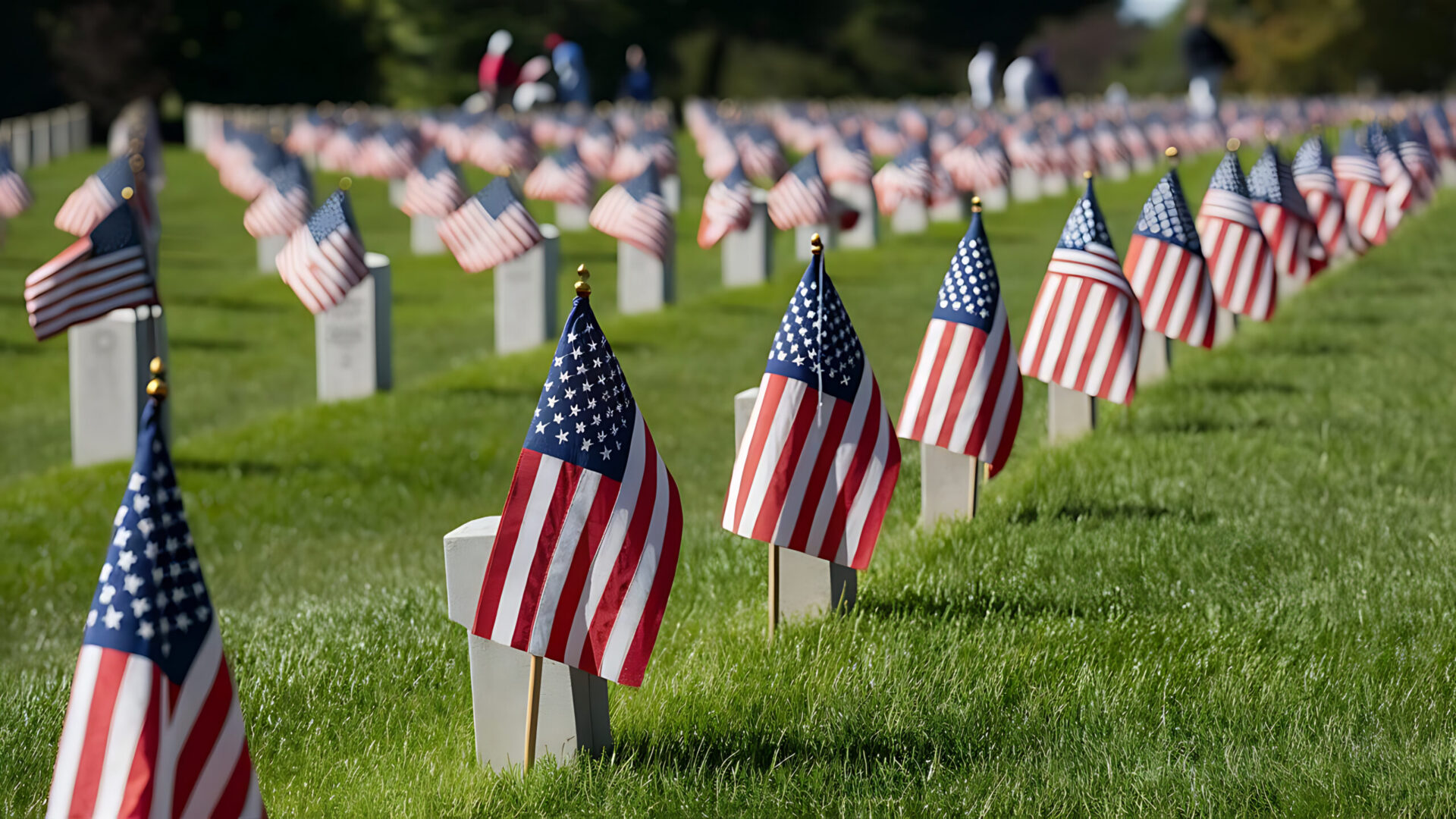 Rows of American flags at cemetery headstones